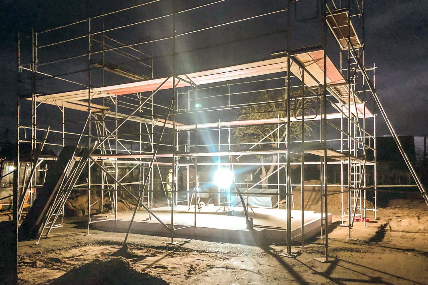 VIVĀN SIGNATURE Compact in Zschepplin bei Leipzig: Baustelle bei Nacht, Gerüst über der Bodenplatte